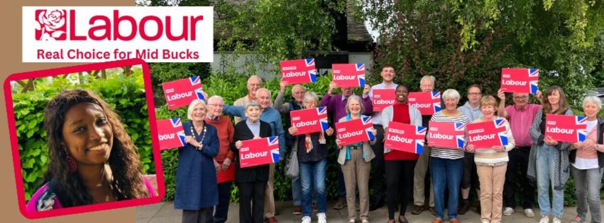 Large group of people, smiling and holding up Labour placards 